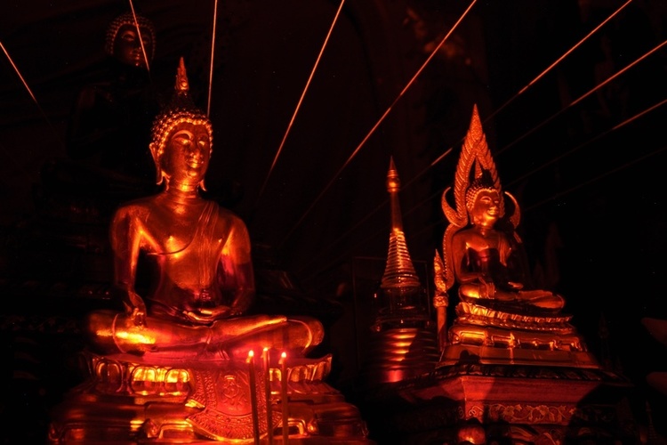 A photo of Buddha images, candlelight, and energy strings.